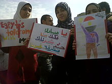 Young protesters in Cairo. The middle sign reads: "Mubarak leave us and go look for someone else to gross out other than us." Cairo female protesters with colorful signs - 1FEB2011.jpg