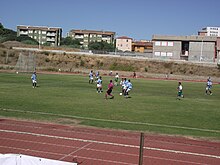 Un'azione del Carbonia (con la seconda maglia celeste) in una partita del Campionato di Eccellenza 2011-12 al campo Giuseppe Dettori