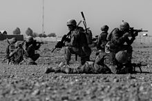 Several soldiers on the ground, aiming rifles in different directions