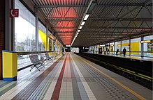 A Brussels Metro station. The elevated third rails for both tracks can be seen halfway between the platforms. Demey station, looking West from the Herrmann-Debroux bound platform (Auderghem, Belgium).jpg