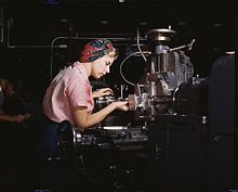 Female machine tool operator at the Douglas Aircraft plant, Long Beach, California in World War II. After losing thousands of male workers to military service, American manufacturers hired women for production positions, to the point where the typical aircraft plant's workforce was 40% female.[16]