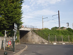 Vue d'une route qui passe sous un pont ferroviaire.