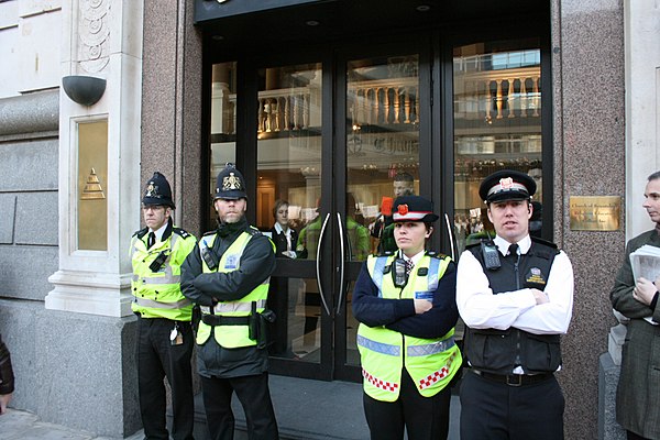 Two PCSOs (right) with two Police Constables of the City of London Police. Note the unique red edging of the reflective bands and the red shield badge