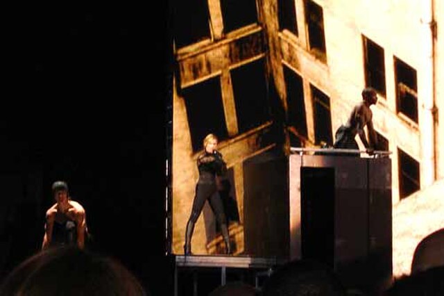 Madonna (center) singing "Jump" while dancers perform parkour routines, on the 2006 Confessions Tour