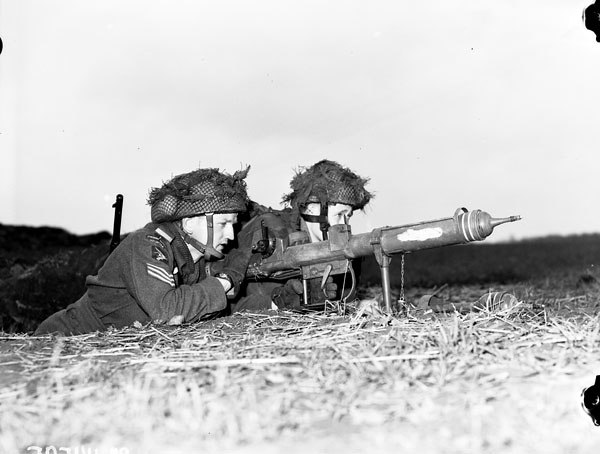 Two Airborne soldiers demonstrate a PIAT antitank weapon.