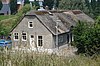 Boerderij met dwars woonhuis, waarin rechts een opkamer. Vensters met zesruitsschuiframen. Stal dwars op het woonhuis aan de achterzijde