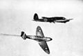 British Supermarine Spitfire fighter aircraft (bottom) flying past a German Heinkel He 111 bomber aircraft (top) during the Battle of Britain (1940)