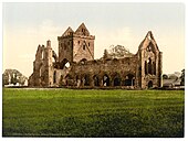 Fotografía en color del siglo XIX que muestra una iglesia parcialmente en ruinas.