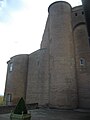 Kleurenfoto van een enorme dubbele toren van rode baksteen.  Het linkerdeel is in hoogte verkleind, waardoor er een schuine afgeknotte wand overblijft.  Aan de rechterkant blijft de oorspronkelijke hoogte bestaan ​​en toont een machicolatie die rust op de hoektorentjes.