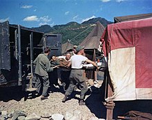 US Army medics move a wounded soldier on a stretcher from a 568th Medical Ambulance Company ambulance into a tent for treatment at the 8225th Mobile Army Surgical Hospital (MASH), Korea, September 1, 1951. Wounded soldier arriving at the 8063rd MASH.jpg