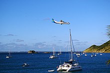 Bucht von Grand-Case mit Kreolen-Fels, im Norden dahinter die Insel Anguilla. Maschine der Air Caraïbes im Landeanflug auf L’Espérance