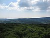 View from the Pferdskopf lookout tower over the upper Weiltal to the Kolbenberg with the transmitter mast (center) in the Taunus main ridge.  To the right of it the Hegewiese.  To the left of the Kolbenberg the Klingenkopf, in front of it the Weisseberg and a little left in front of it the Great Oak Forest with part of Dorfweil.  Right edge of the picture the Große Feldberg with Arnoldshain below left and Schmitten in front