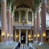 interior of the church, view to the organ, light pink columns, grey benches, organ case white and gold