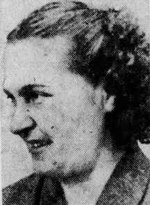 A white woman in profile, smiling, with dark hair drawn back from her face