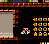 Wario dashes through a thin wall to find a secret room full of coins. Wario Land II gameplay.png