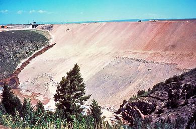 The dark brown streak on the dam face near the gray bedrock in the left half of the photo is a leak that formed on the morning of June 5. The speck above the leak near the top of the dam is a D-9 bulldozer on its way to push dirt into the leak.