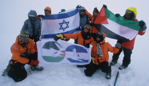 The joint Israeli and Palestinian team display flags of their countries atop The Mountain of Israeli-Palestinian Friendship