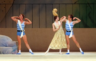 Bailarina con vestido largo de 1920 y tocado de plumas, con dos bailarines vestidos como atletas bailando a cada lado de ella