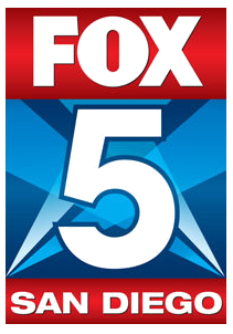 A narrow rectangular logo. The top part is red and has the Fox network logo in white. The middle is blue with light blue searchlights in the background and a large white 5, trimmed in blue, in the middle. Beneath in white on a red box are the words "San Diego".