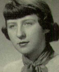 A young white woman with hair cut in straight dark bangs, wearing a neckerchief