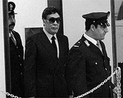 Buscetta (in sunglasses) is led into court at the Maxi Trial, circa 1986