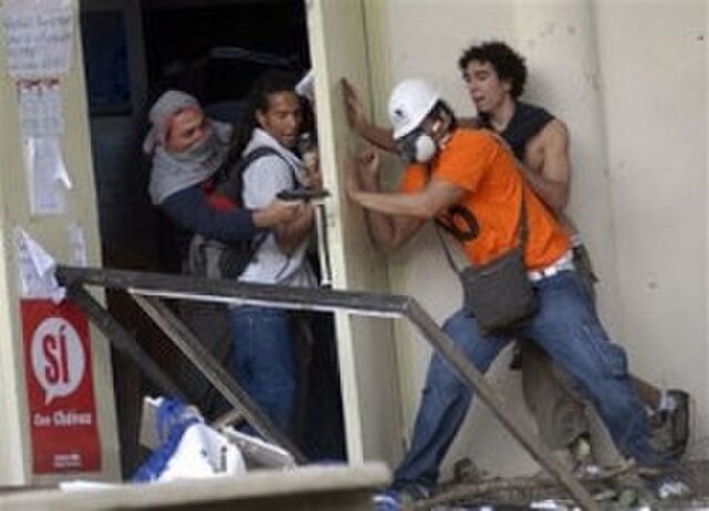 Two students of the Central University of Venezuela wrestle with two government supporters, one of them armed, on 7 November 2007. One of the students
