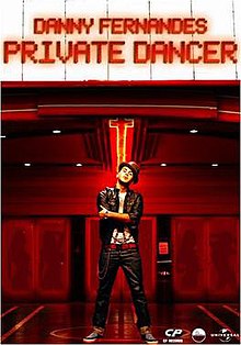 Danny pose di depan teater masuk di mana marquee memiliki nama-nya dan judul lagu yang ditulis dalam neon huruf merah.