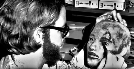 Robert A. Burns applies paint to a latex mold cast, designing the first of three masks used in the original film.