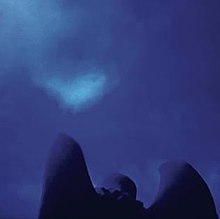 A blue photograph of a sky taken over the shoulders and wings of an angel statue