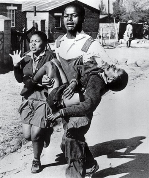 Hector Pieterson being carried by Mbuyisa Makhubo after being shot by the South African police. His sister, Antoinette Sithole, runs beside them. Piet