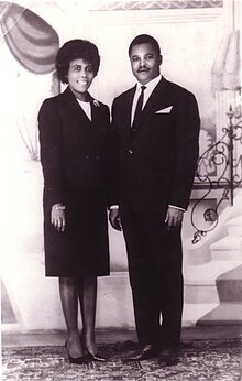 A well-dressed man and woman smile at the camera,