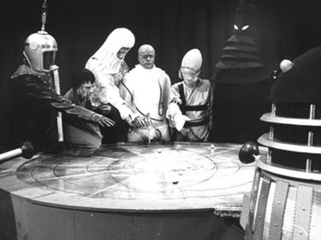 A production still showing the Daleks colluding with the masters of the Fifth Galaxy. Critics praised the costumes and set design.