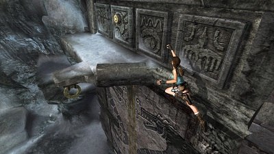 A gameplay screenshot from Tomb Raider: Anniversary, showing Lara jumping for a ledge below a door switch. While many mechanics within the Tomb Raider