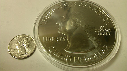 A normal-sized quarter (left) sitting next to a bullion coin in a plastic holder (right)