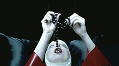 Gaga dressed as a nun in a red latex habit, swallowing rosary beads. The Catholic League criticized the video's religious imagery.