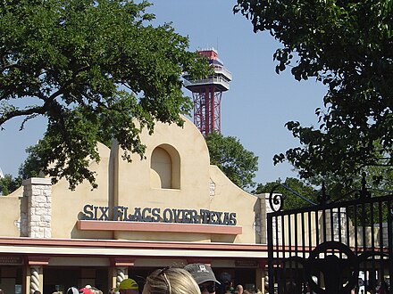 The entrance of Six Flags over Texas welcomes visitors while the Oil Derrick observation tower looms in the background.