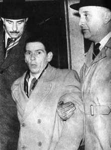 Man being escorted by two taller men on either side of him