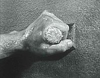 The hand holding the stamp belongs to Harold C. Nyby, Jack Webb's construction foreman. (The logo is a moving image with sound, of which a still is displayed here.) Mark VII logo 1953(1).jpg