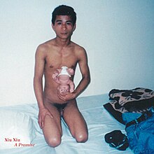 Photo of a naked man kneeling and holding a baby doll upside-down.