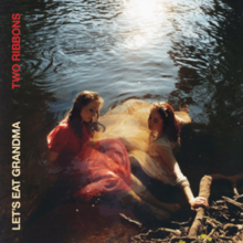 A photo of the two members of Let's Eat Grandma, Rosa Walton and Jenny Hollingworth, sat in water along a grassy, branch-covered shore. The band and album names are vertical along the left side.