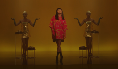 A screenshot of a scene in the music video of "Nirvana", portraying Inna in a gold box accompanied by two women with their arms out. A critic interpreted it as Egypt-inspired. Nirvana Inna.png