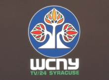 WCNY-TV used a logo patterned after the sugar maple tree, the state tree of New York, from 1965 to 2001; the autumnal color version seen here debuted after the station began broadcasting to color in 1971. WCNY-TV logo, 1971.webp