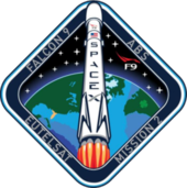 Ein rautenförmiges Emblem mit blauen Rändern, das eine künstlerische Darstellung einer Rakete des Typs Falcon 9 zeigt, die in den Weltraum startet.