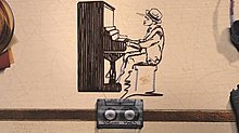 Bruno Mars arranging himself in a cassette tape in the shape of him playing the piano, in the music video.