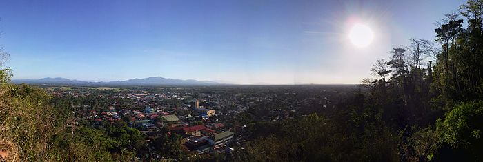 Rosario, Batangas-urbosilueto kun la urbocentro pri la malfono kaj rizejoj (kie Rosario estas konata pro) kaj montoj sur la fono.