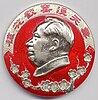 Badge with a portrait of Chairman Mao in the centre, Chinese writing above and a branch of plum blossom below