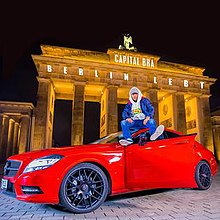 Hauptstadt Bra sitzt auf einem roten Mercedes-Benz vor dem Brandenburger Tor in Berlin.