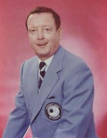 Middle-aged man wearing light blue suit jacket with a CBC Sports crest