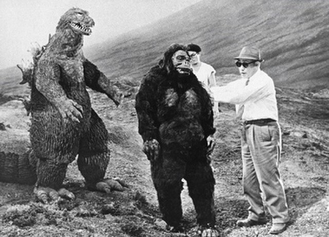 Eiji Tsuburaya directs Shoichi Hirose (in the King Kong suit) and Haruo Nakajima (in the Godzilla suit) on the Mount Fuji set during filming.