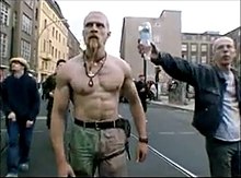 A man offers an inverted bottle of water to the Techno Viking. Technoviking.jpg